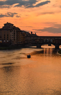 Buildings by sea against orange sky