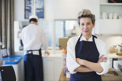 Portrait of confident female owner standing arms crossed in cafe