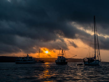 Silhouette boats sailing on sea against sky during sunset