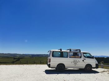 Vintage car on field against clear blue sky