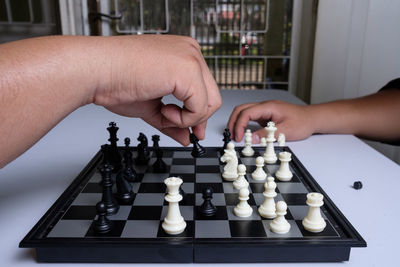 Cropped hands of parent and child playing chess on table