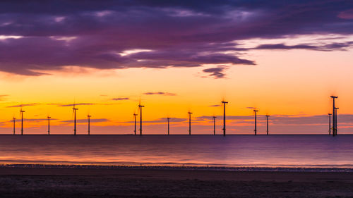 Scenic view of beach against dramatic sky during sunset