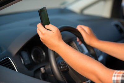 Close-up of man working with smart phone while driving