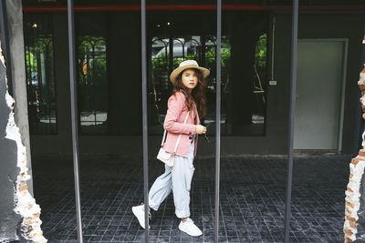 Portrait of smiling girl standing against glass wall