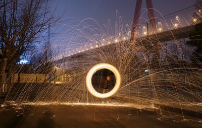 Man spinning wire wool on street at night