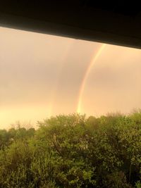 Scenic view of rainbow over field during sunset