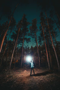Rear view of man standing on field at night