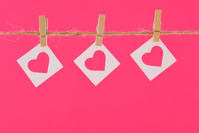 Close-up of love hanging over pink background