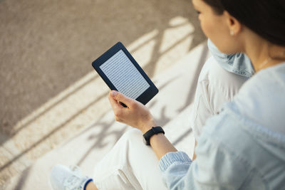 Woman reading an e-book while sitting on steps