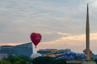 Hot air balloon flying over city against sky during sunset