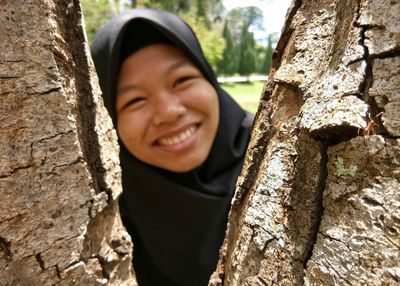 Portrait of smiling girl standing against tree trunk