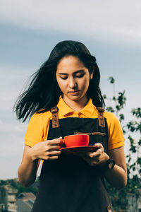 Young woman holding ice cream standing outdoors