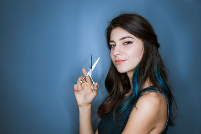 Brunette hairdresser smiling and holding professional scissors in hands