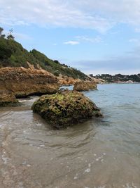 Rock formations on shore against sky