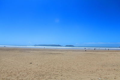 Scenic view of beach against clear blue sky