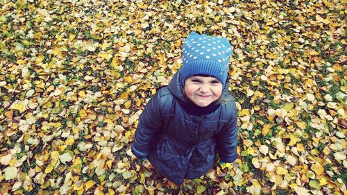 High angle view of smiling girl standing on fallen autumn leaves
