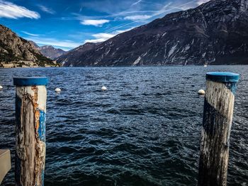 Wooden post by lake against mountains during winter