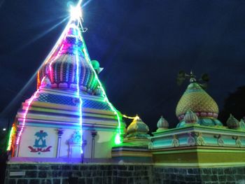 Low angle view of statue against illuminated building at night