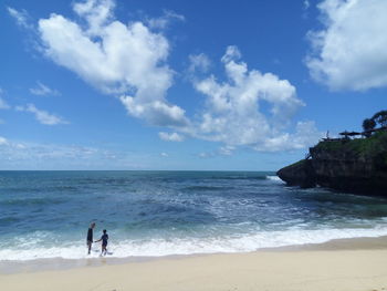 People standing on beach against sky