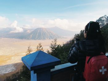 Rear view of man looking at snowcapped mountain against sky