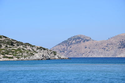 Scenic view of sea and mountain against clear blue sky