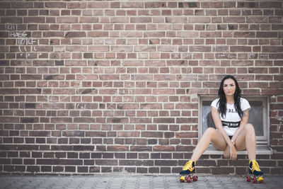 Young woman standing on brick wall