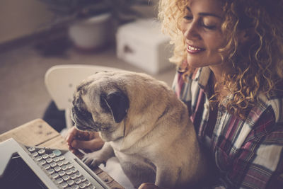 High angle view of woman with pug using typewriter
