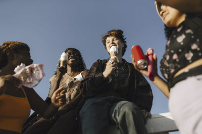 Smiling multiracial friends with ice creams on sunny day