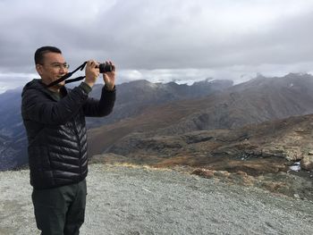 Man photographing on mountain against sky