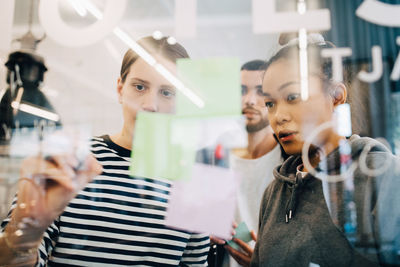 Multi-ethnic hackers discussing strategy over glass at creative office