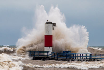 Lighthouse by sea against sky