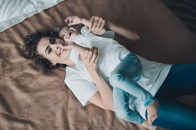 High angle view of mother lying on bed with daughter