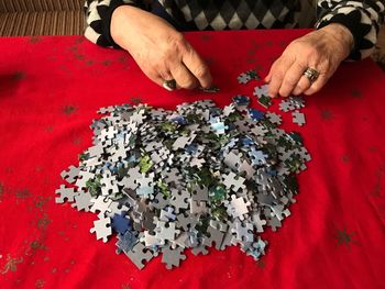 Midsection of senior woman assembling jigsaw puzzle pieces on table