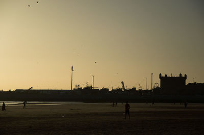 Silhouette man on beach against sky during sunset