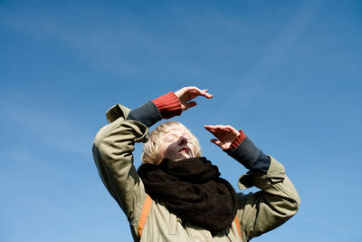 Low angle view of boy against blue sky