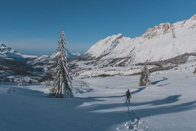 An unrecognizable male hiker wearing snowshoes walking in the french alps