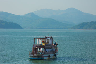 Boat sailing in sea against mountains