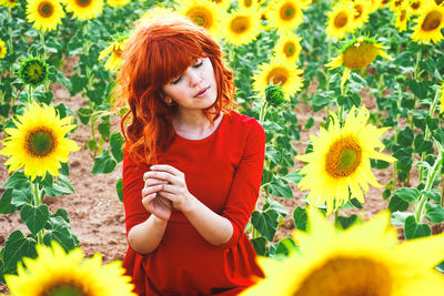 Smiling young woman with yellow flowers in field