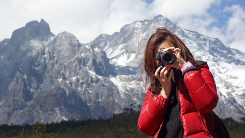 Woman photographing against mountain range