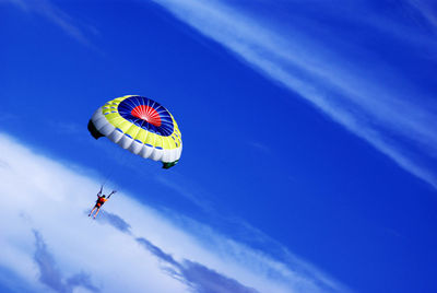 Low angle view of man parachuting against sky