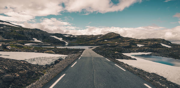 Road amidst snowcapped mountains against sky