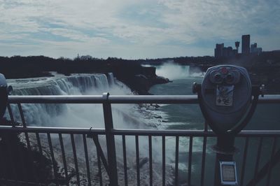 Coin-operated binocular by niagara falls against sky