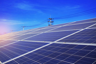 Low angle view of electricity pylon against blue sky