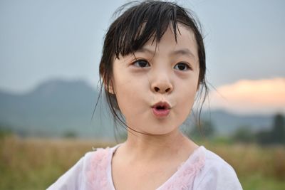 Close-up of girl with mouth open looking away against sky