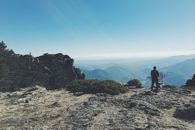 Rear view of man standing on rock against sky