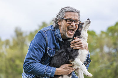 Portrait of happy senior man cuddling his dog