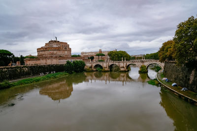 Castelo sant'angelo and ponte sant'angelo over tiber river - cloudy overcast grey day - rome, italy