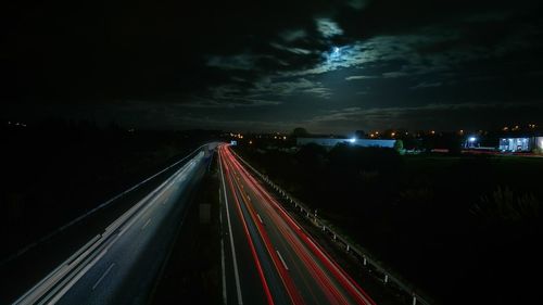 Light trails on road in city against sky at night