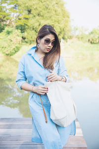 Woman with bag standing at jetty over lake