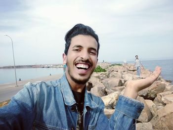 Portrait of smiling young man standing at beach